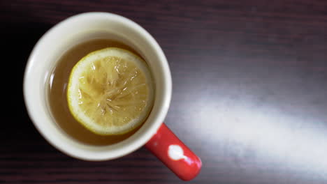 a cup of lemon tea on a wooden table