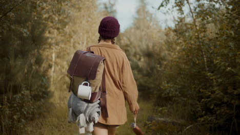 mujer con mochila y botella caminando en el bosque