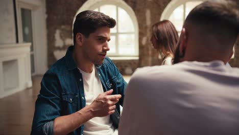 A-brunette-man-in-a-blue-denim-jacket-and-a-white-T-shirt-communicates-with-a-bearded-man-in-a-pink-T-shirt.-Communication-in