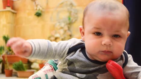 close up of cute baby playing with the toy telephone on his walker then looks at camera