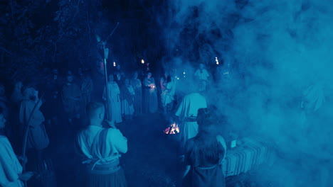 nighttime gathering with torches and campfire
