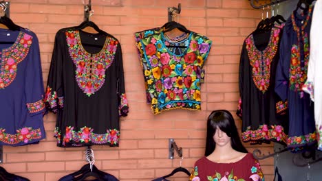 camera pans left showing black and colorful huipil blouses in merida, mexico