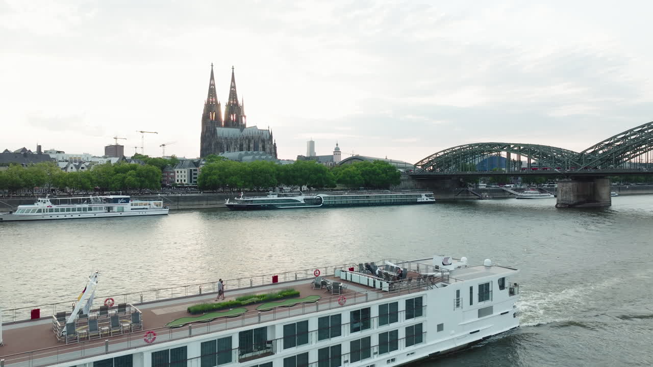 드론은 슬로우 모션으로 라인강의 배를 촬영하고, 드론이 올라가면 석양에 쾰른 대성당이 보입니다.