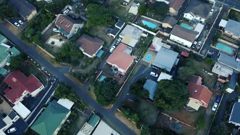 Imágenes-Aéreas-De-Un-Dron-De-Casas-Residenciales-Con-Una-Carretera-Con-Tráfico-En-Movimiento-Con-Vistas-A-Un-Centro-Comercial-De-Torre-De-Agua-Y-Un-Campo-De-Golf-Con-Un-Parque-De-Hierba-Verde