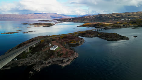 Aerial-orbit-above-placid-calm-waters-and-cottage-on-the-cliffs-by-the-Skye-bridge