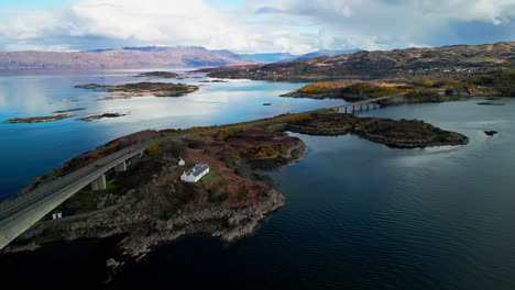 aerial orbit above placid calm waters and cottage on the cliffs by the skye bridge