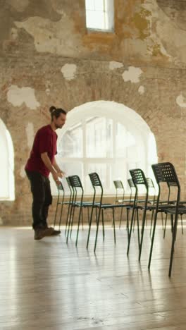man arranging chairs in a large room