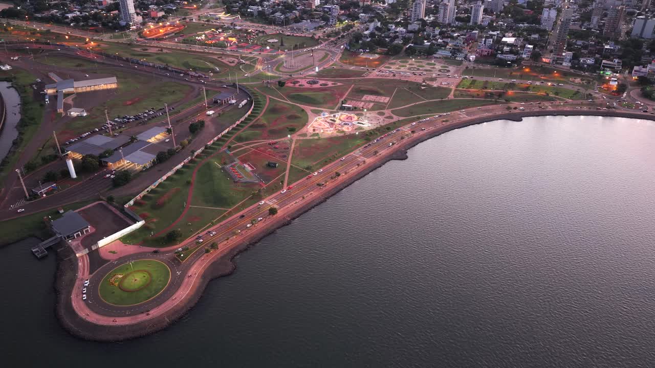 Aerial view of a waterfront urban park with curved road and small roundabout near the Paraná river at Posadas, Cuarto Tramo, Misiones, Argentina.