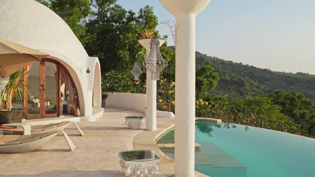 Oasi tropicale con piscina a sfioro che si affaccia sulle montagne al tramonto.