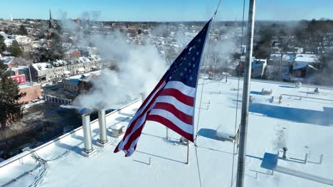 smoking chimneys on top of roof with waving american flag in american town