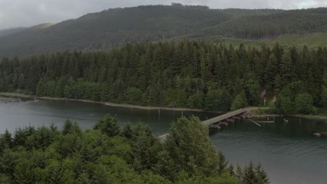 drone flying towards the bridge in port renfrew, british columbia, on a cloudy day