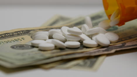 pill bottle pours out white pills onto stacks of money