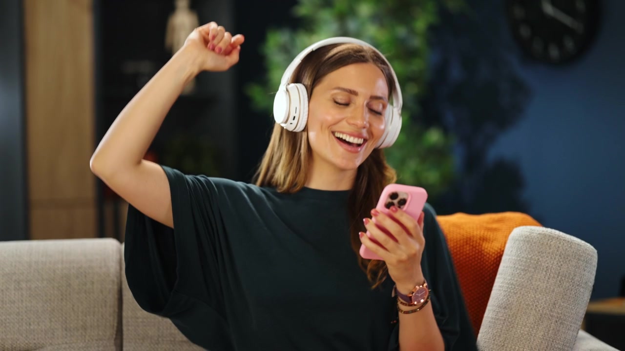 Giovane donna che si rilassa sul divano ascoltando musica con le cuffie.