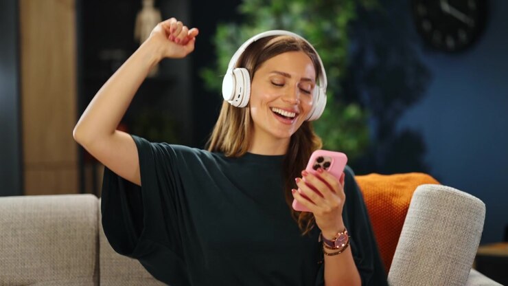 Giovane donna che si rilassa sul divano ascoltando musica con le cuffie.