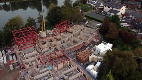 aerial view looking down over care home construction development progress in rural british village next to fishing lake