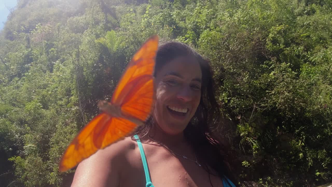 el selfie de la mujer latina del río es fotobombardeado por una mariposa naranja voladora