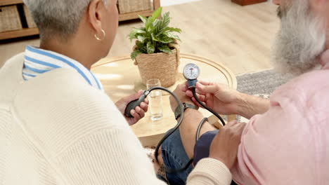 checking blood pressure, senior couple monitoring health at home together
