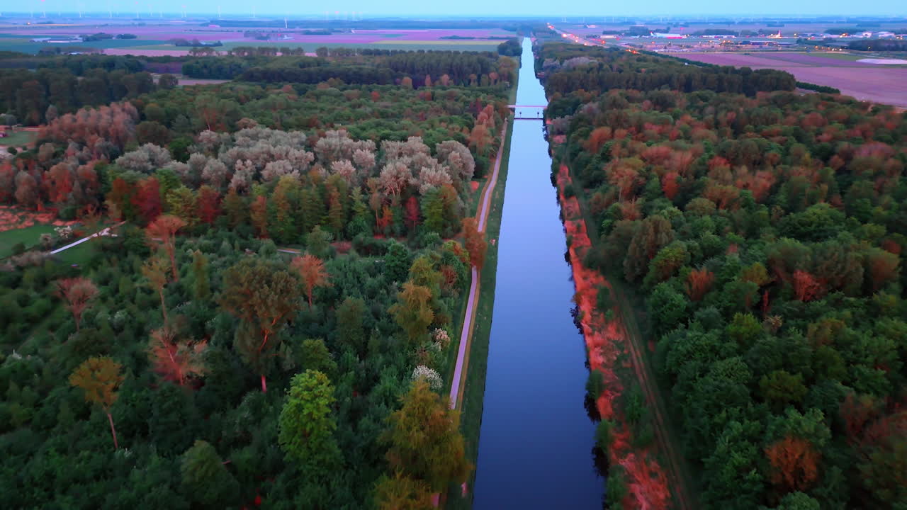 Autumn trees by a canal. Aerial view of a serene canal bordered by trees showcasing vivid autumn colors under a clear blue sky