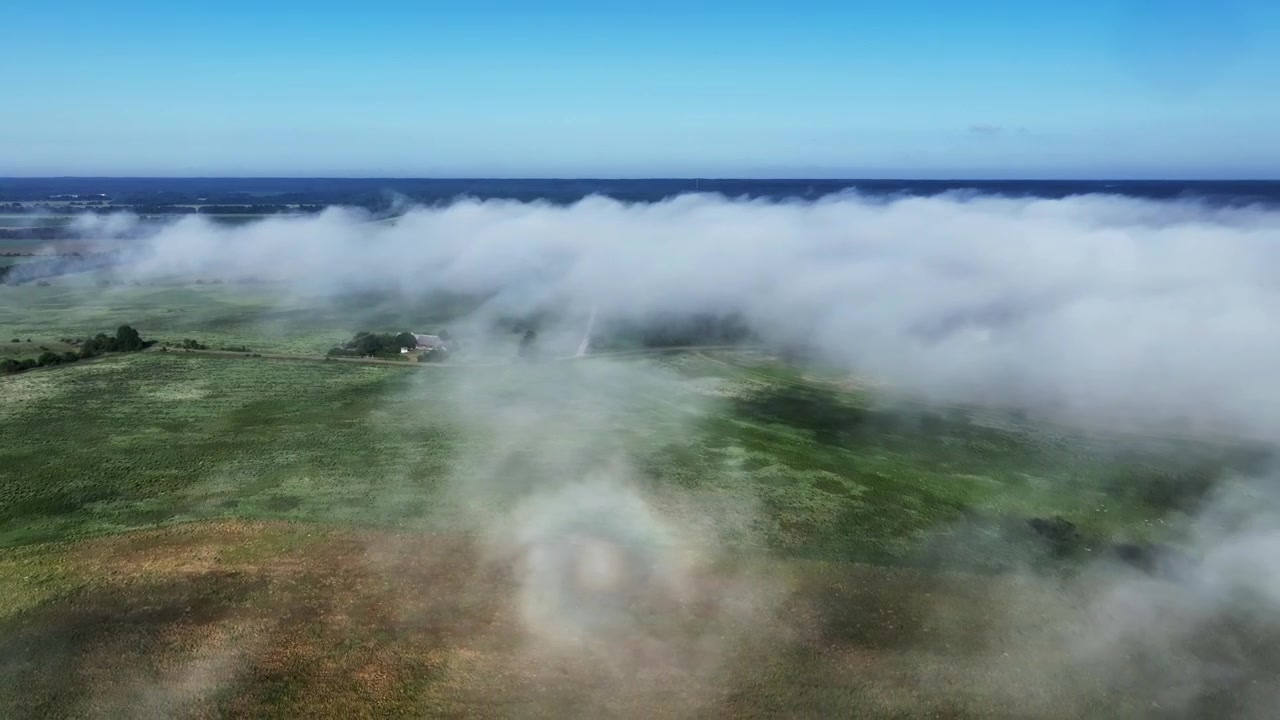 Volo di drone su un paesaggio nebbioso, un alone luminoso appare sulla superficie della nebbia. Saaremaa, Estonia.