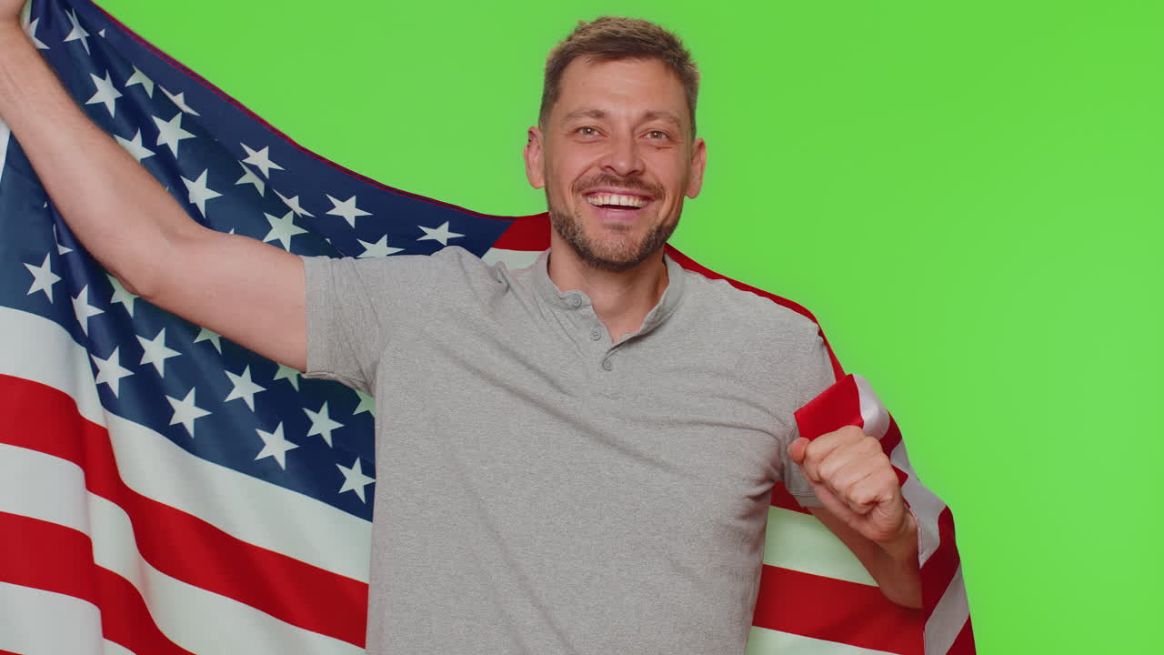 joven barbudo agitando y envolviéndose en la bandera estadounidense, celebrando los derechos humanos y las libertades