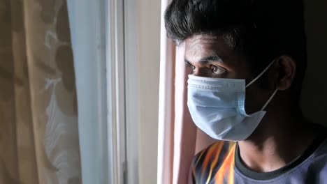 young person wearing mask looking out window