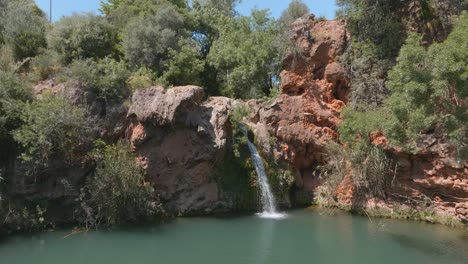 Ein-Wasserfall,-Der-Vor-Dürren-Bäumen-In-Einer-Wüstenähnlichen-Landschaft-Versteckt-Ist,-Offenbart-Eine-Oase-An-Der-Algarve