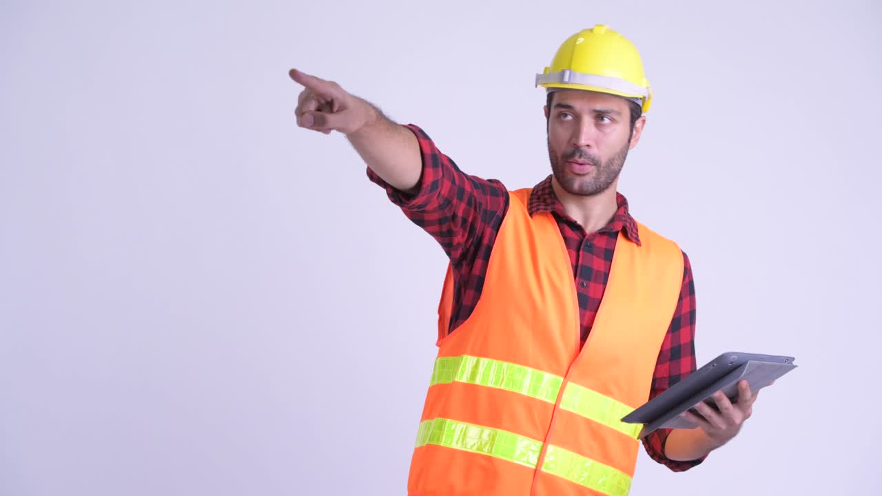 hombre persa barbudo y guapo trabajador de la construcción con una tableta digital