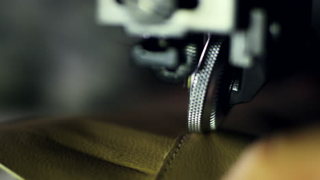 tailor working on sewing machine at textile factory. close up leatherworker hand