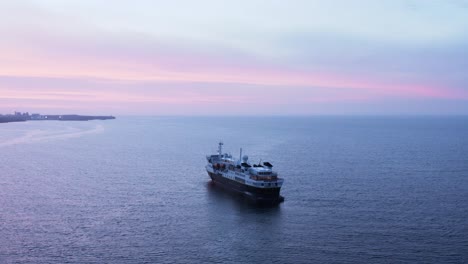 natgeo passenger cruise ship stationary in calm ocean water with purple sunset