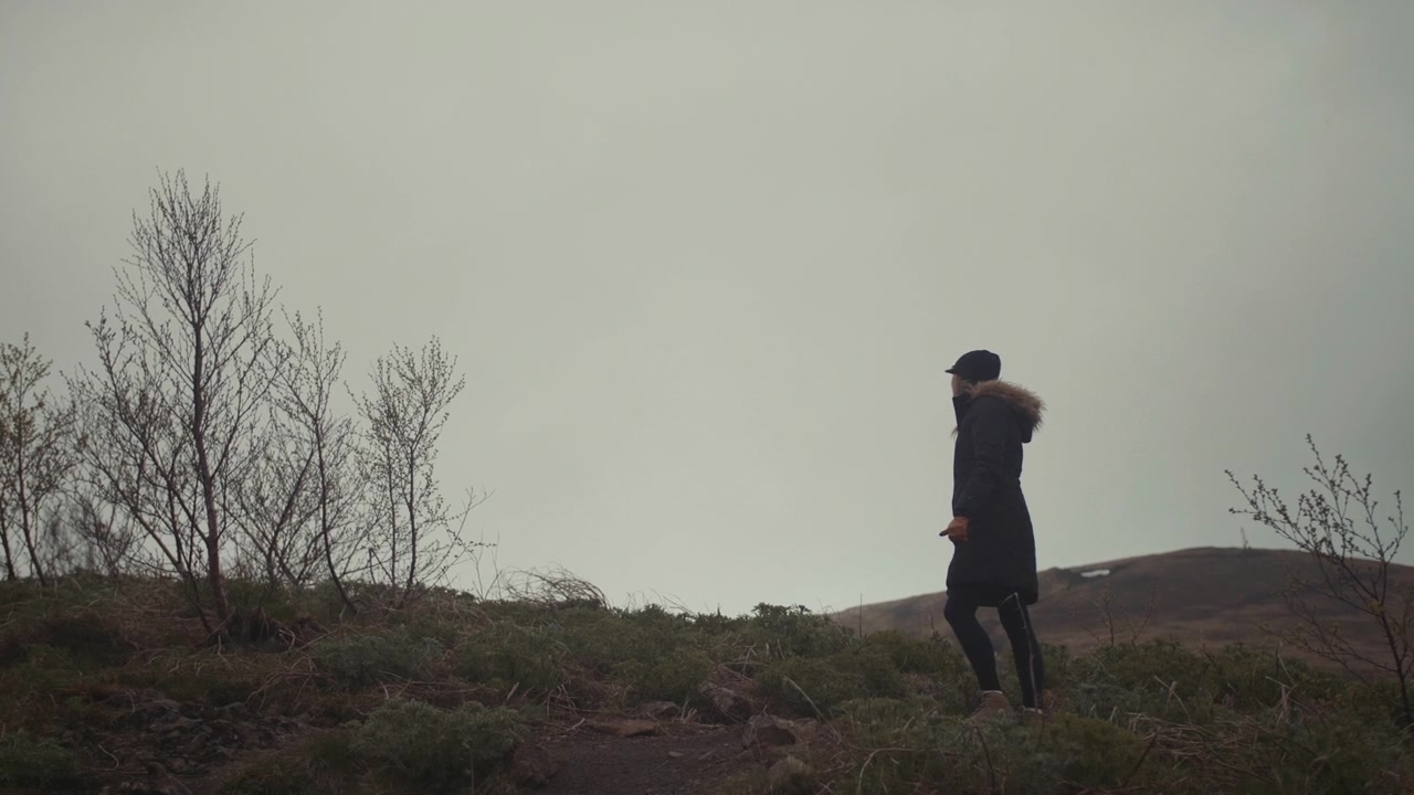 Donna con cappotto invernale che cammina su una collina nella natura