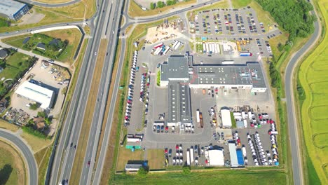 Aerial-view-of-the-logistics-park-with-warehouse,-loading-hub-and-many-semi-trucks-with-cargo-trailers-standing-at-the-ramps-for-load-unload-goods-at-sunset