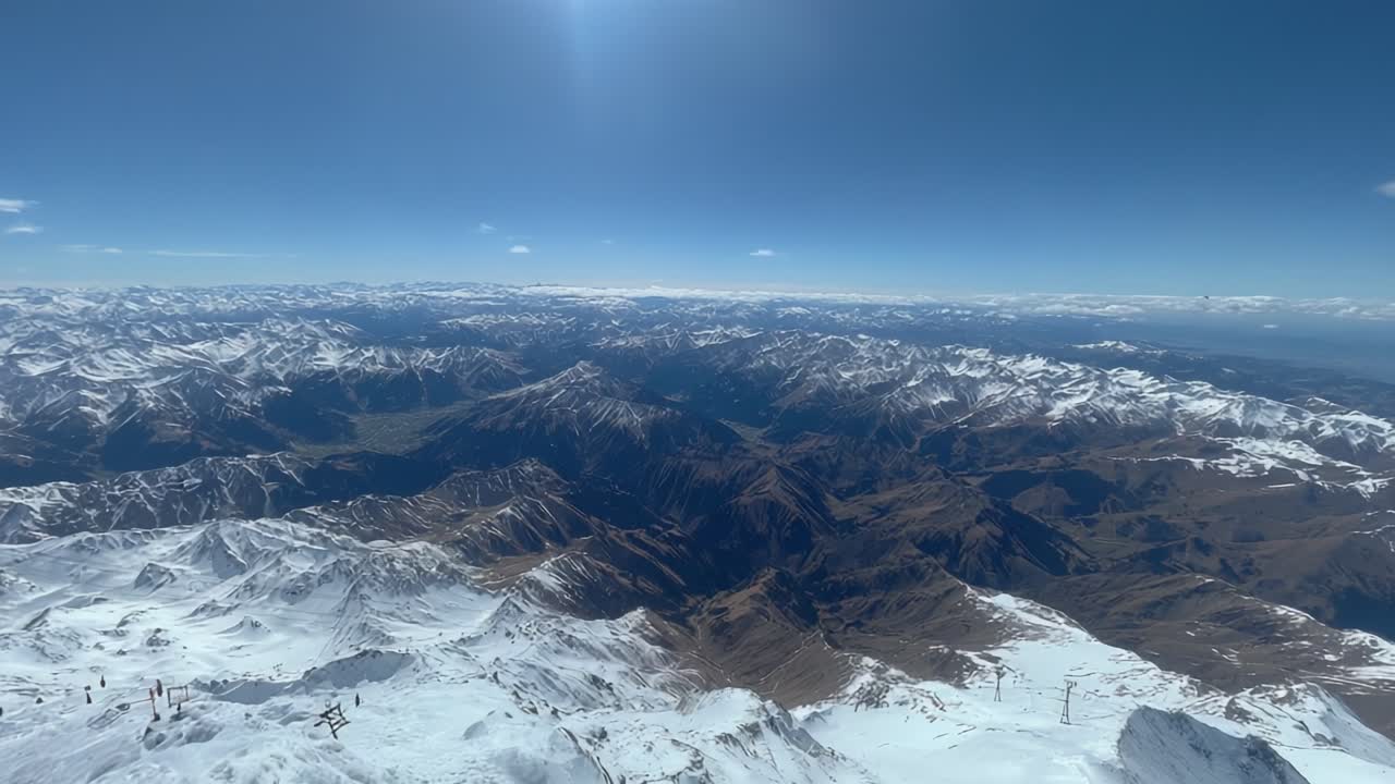 Breathtaking Aerial View of Majestic Snow-Capped Mountains Under a Clear Blue Sky, Showcasing the Vast Wilderness and Stunning Natural Landscape