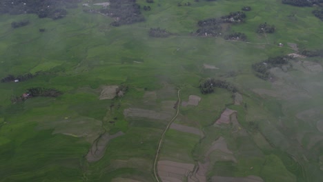 Revelar-Toma-De-Paisajes-De-Campos-De-Arroz-Verde-Con-Nubes-Bajas-En-La-Isla-De-Sumba,-Antena