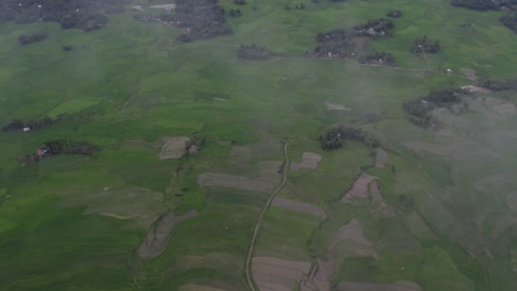 fotografía de campos de arroz verdes con nubes bajas en la isla de sumba, desde el aire
