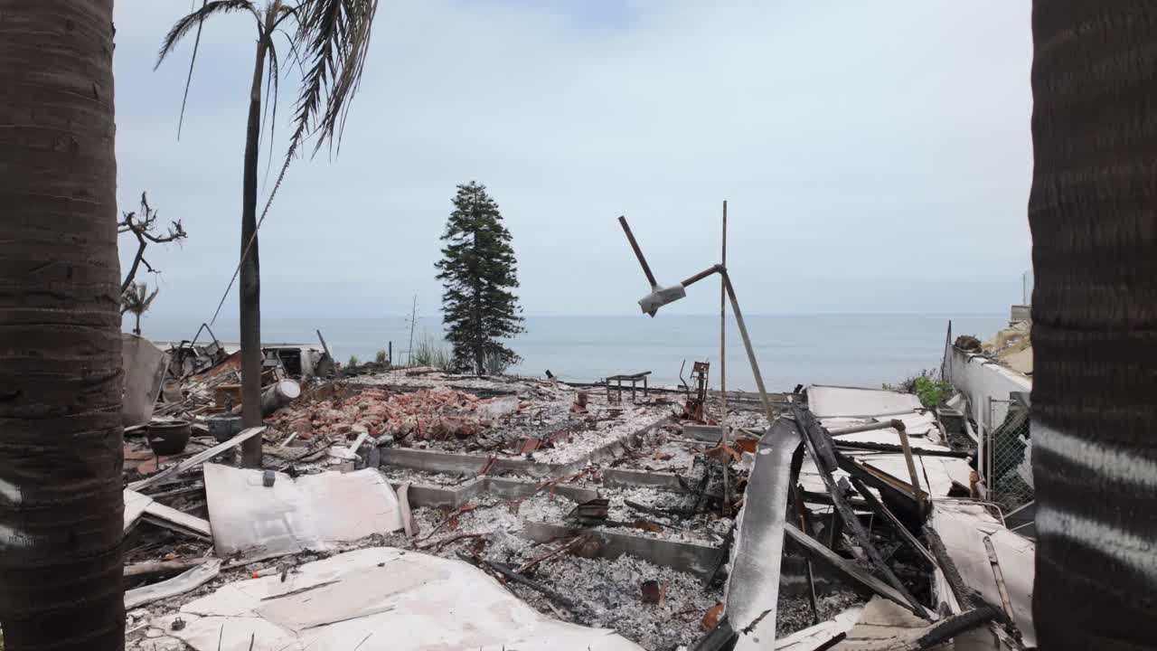 Gimbal wide booming down shot of an ocean view home in Sunset Mesa burned by the Palisades Fire in Malibu, California. 4K