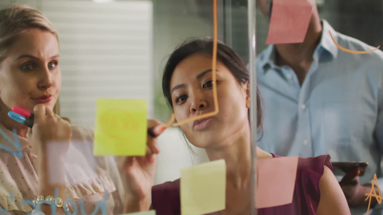 Professional businesspeople discussing while writing on the whiteboard in modern office in slow moti