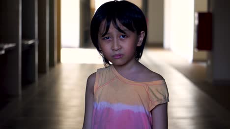 Retrato-De-Un-Joven-Del-Sudeste-Asiático-Solo-Asustado-Mirando-A-La-Cámara-En-Un-Pasillo-Abandonado-Del-Centro-Comercial-Con-Luz-Y-Sombra-En-El-Fondo