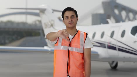 desilusionado trabajador del personal de tierra del aeropuerto indio mostrando los pulgares hacia abajo