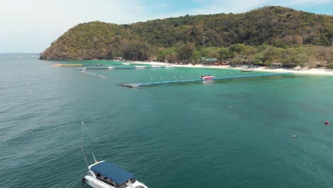 crystal-clear exotic waters of koh hey with floating platform dock, in thailand - aerial low angle orbit survey shot