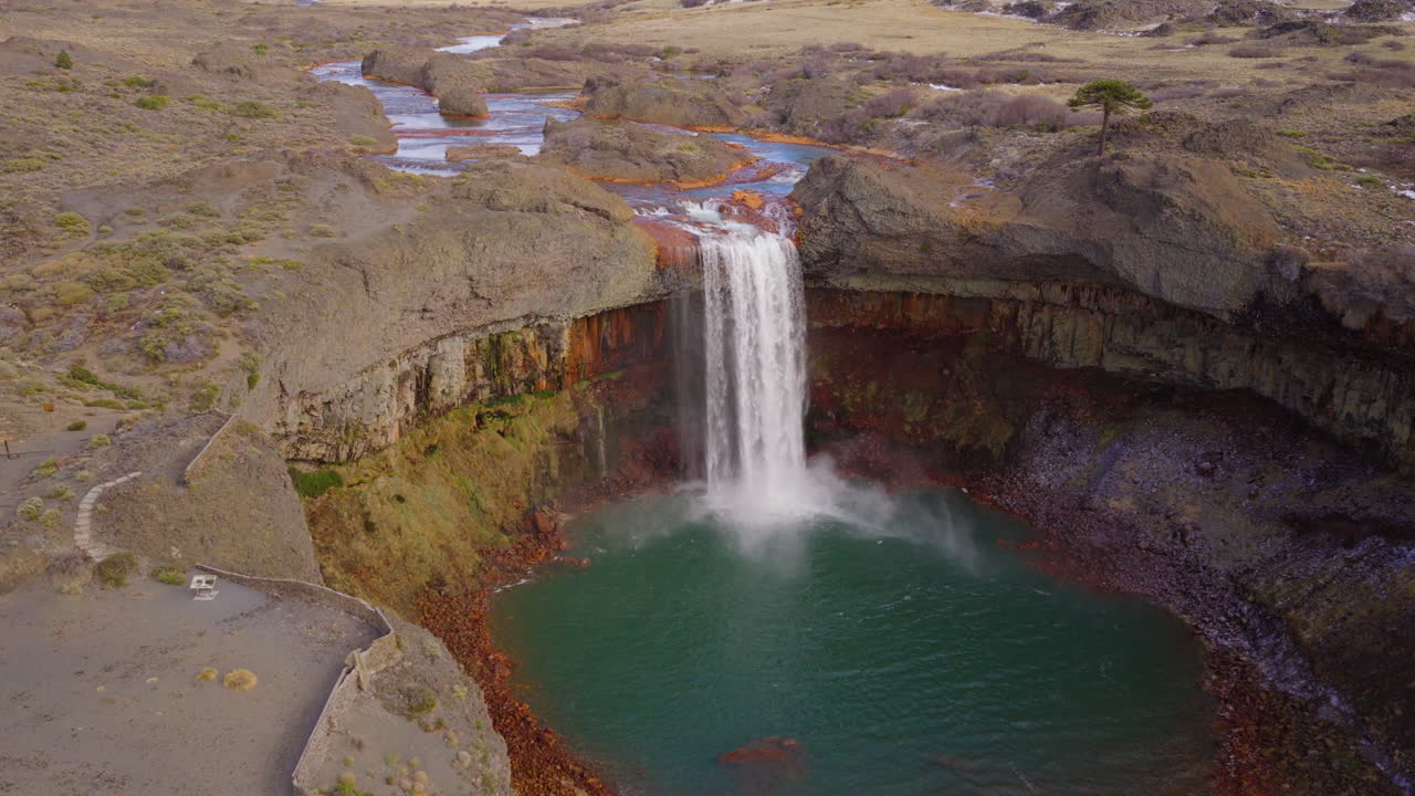 Panoramic aerial fly from striking Salto del Agrio waterfall plunging into the river bay in a rocky Patagonian volcanic canyon, Neuquén, Argentina