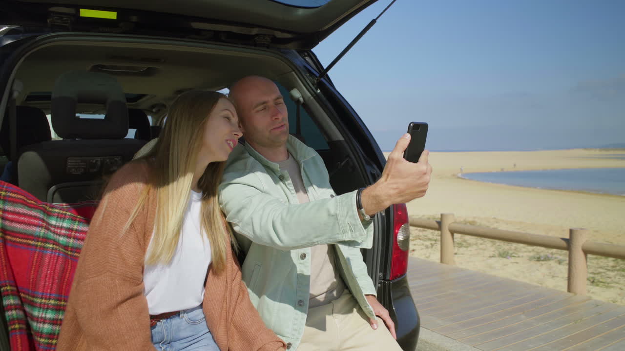 자동차에서 스마트폰으로 사진을 찍는 커플