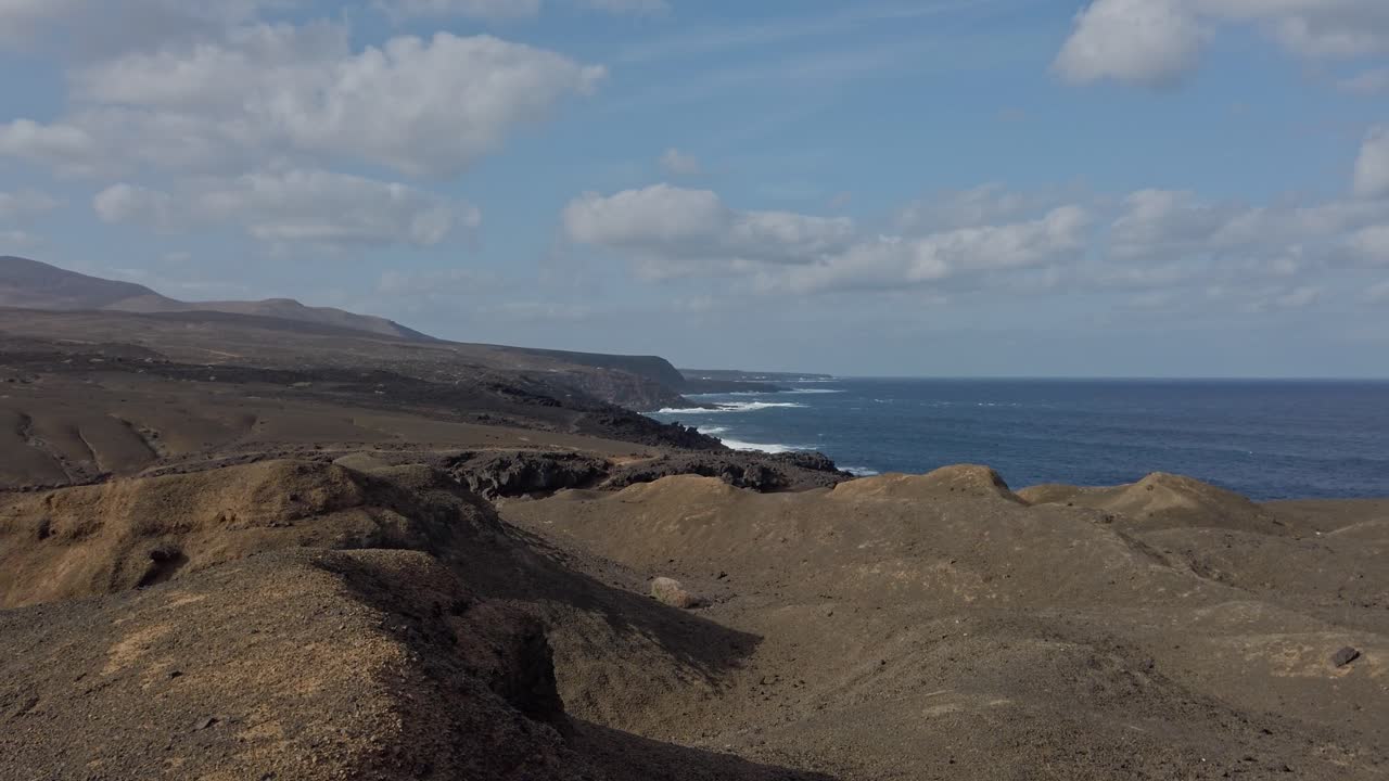 Volcanic landscape meets the vastness of the atlantic ocean on the captivating shores of lanzarote, where rugged terrain and azure waters converge under a canvas of clouds