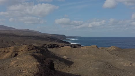 volcanic landscape meets the vastness of the atlantic ocean on the captivating shores of lanzarote, where rugged terrain and azure waters converge under a canvas of clouds