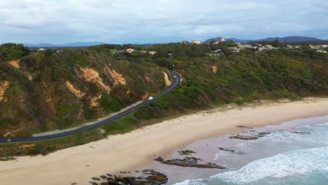 Wide-drone-shot-of-Shelly-Beach-with-coastal-highway-and-ocean-waves-at-Nambucca-Heads-New-South-Wales-Australia