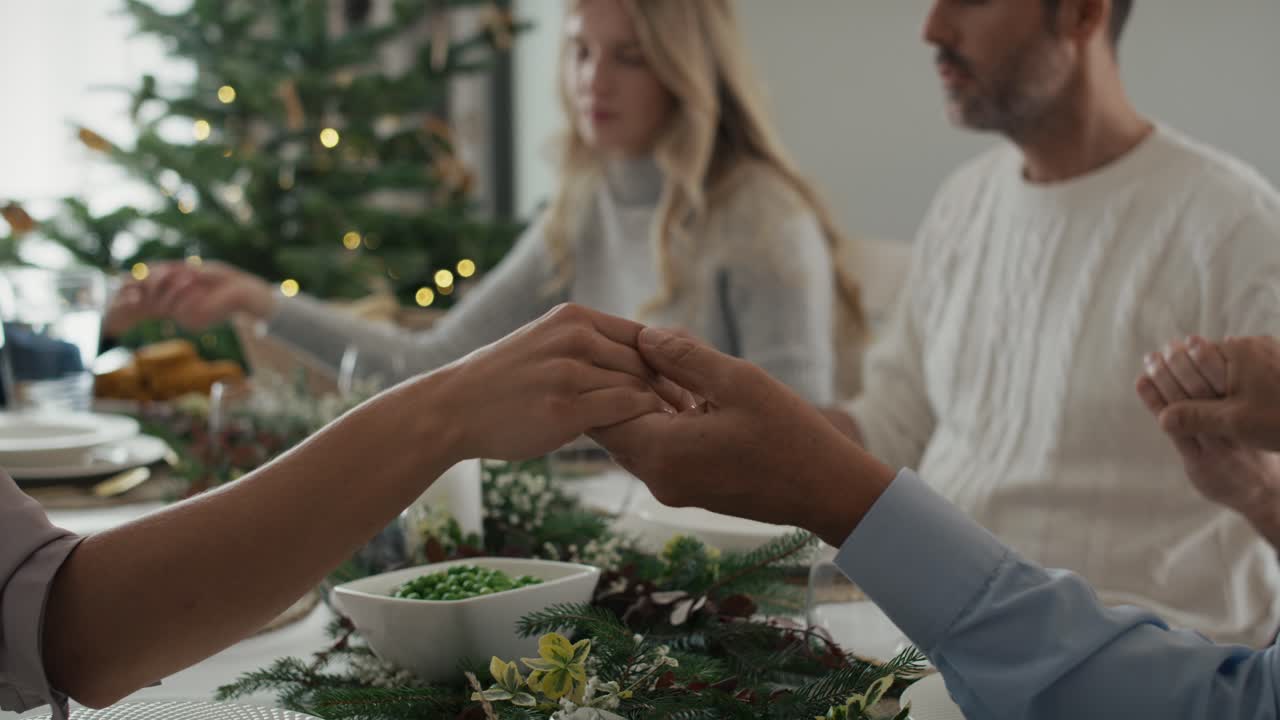 Close up of family's hands holding together around the table and praying.
