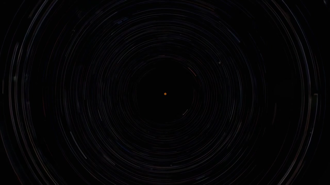 Starting timelapse camera capturing rotation of concentric star trails in polar sky, orange dot