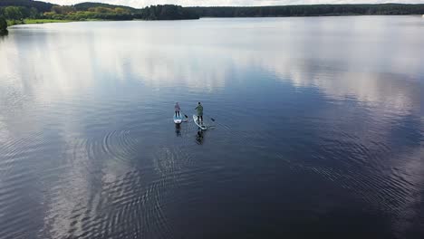 couple paddleboarding on a calm lake