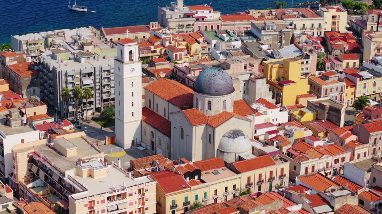 Veduta estiva colorata di una città costiera in Sicilia, che mostra case vivaci.