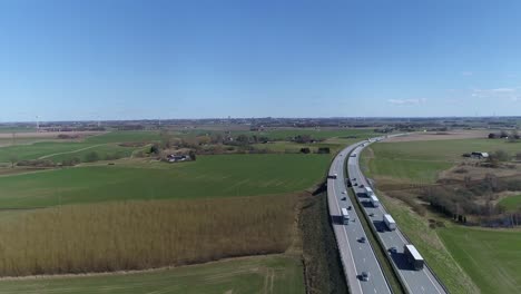 Beautiful-green-farmland-fields-line-bend-in-bustling-highway-in-Sweden