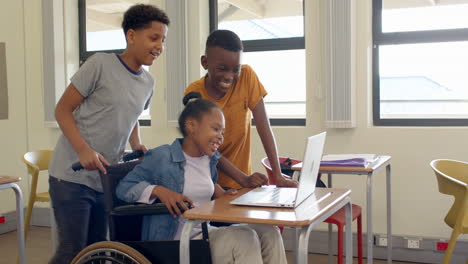 multiracial students using on laptop in classroom, smiling and engaged in learning, at school